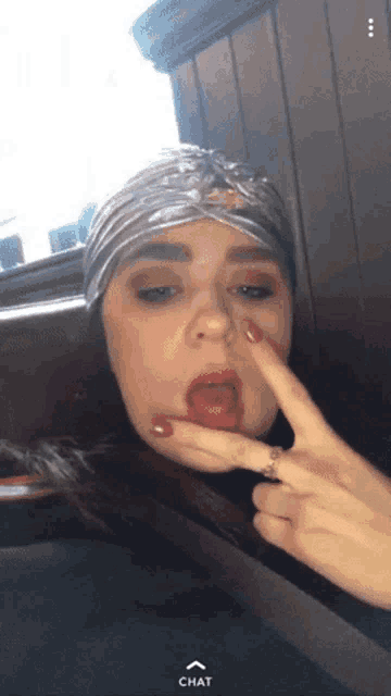 a woman wearing a turban and a ring is making a funny face with her finger