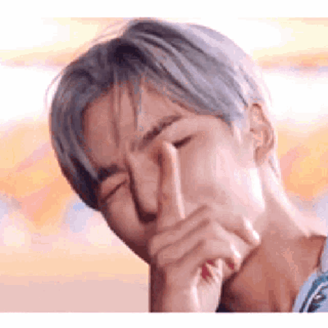 a man is covering his nose with his hand .