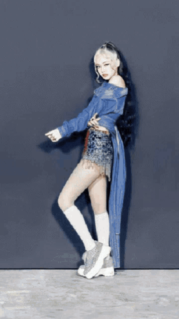 a woman wearing a blue jacket and white socks is standing on one leg