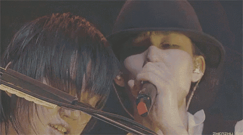 a man in a black hat is playing a violin with his eyes closed