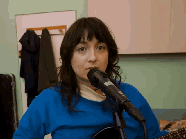 a woman singing into a microphone with a sticker on it that says ' a '