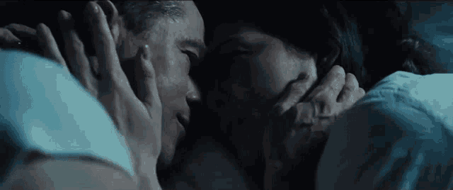 a man and a woman are laying in bed and kissing each other .