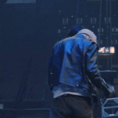 a man in a leather jacket is holding a microphone in his hand