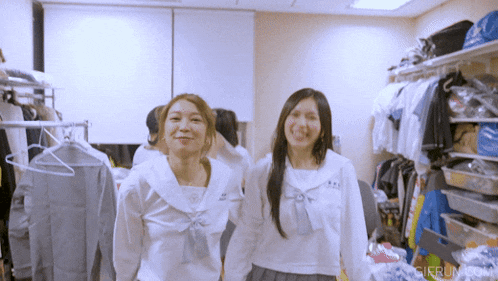 two women in school uniforms are standing next to each other in a room with a gifrun.com logo on the bottom