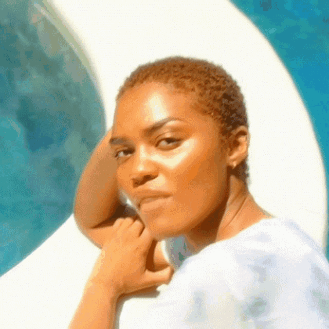 a close up of a woman 's face with her hand on her chin in front of a pool .