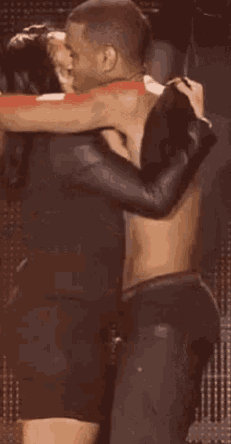 a shirtless man is hugging a woman on stage .
