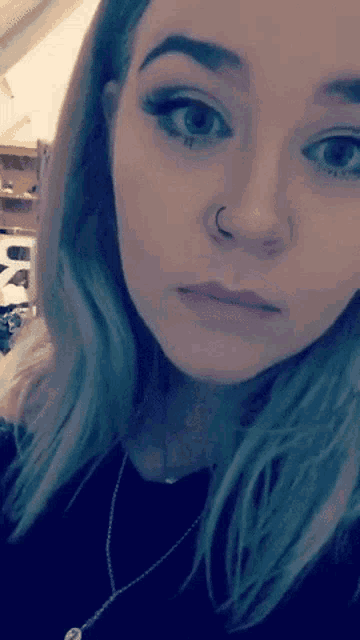 a close up of a woman 's face with a nose ring on her nose