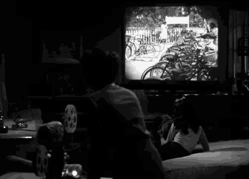 a black and white photo of a person watching a movie