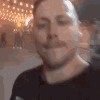 a man with a mustache is making a funny face in front of a crowd of people .