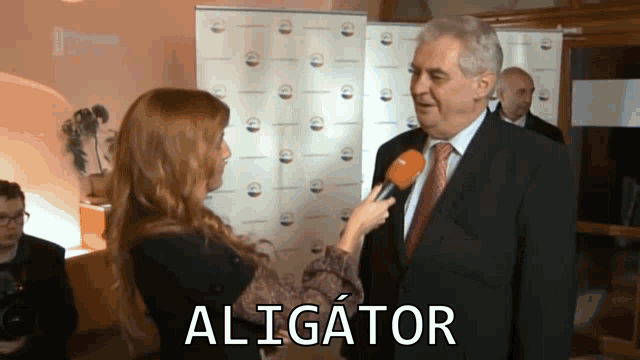 a man in a suit and tie is being interviewed by a woman with the word aligator written on the bottom