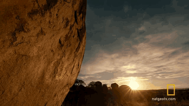 a national geographic video shows the sun setting behind a rock