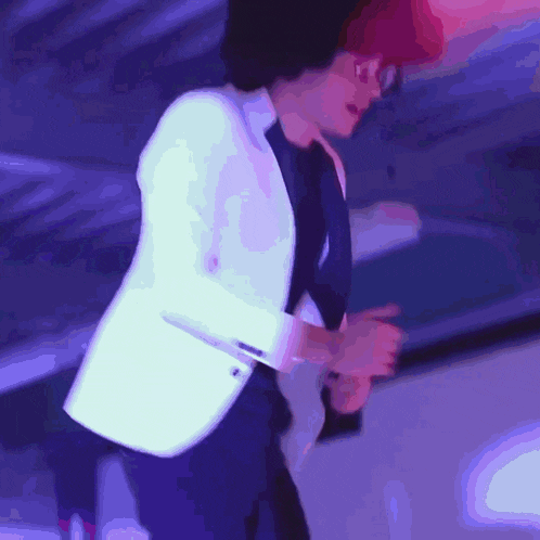 a man in a white jacket and black shirt is dancing