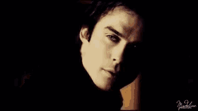 a close up of a woman 's face in a dark room with a man in the background .