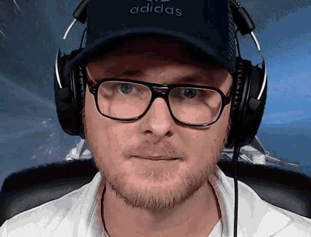 a man wearing glasses and headphones has an adidas hat on