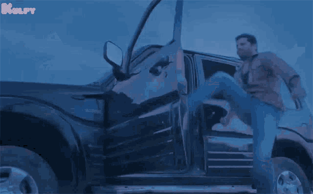 a man is kicking another man out of a car with his leg .