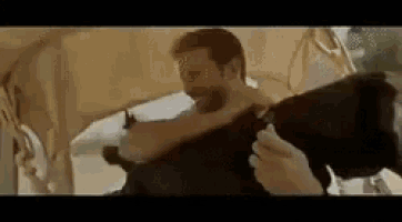 a man is holding a cow in his arms while another man holds a gun .