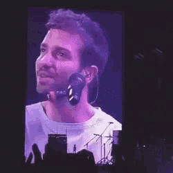 a man is singing into a microphone while wearing headphones on a stage .