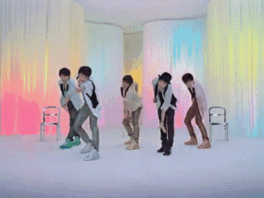 a group of young men are dancing in front of a colorful backdrop