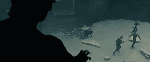 a group of people are playing a game in a dark room while a man wearing a virtual reality headset watches .