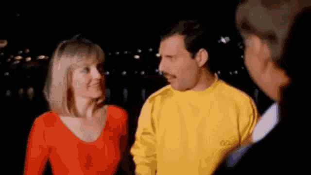 a man and a woman are standing next to each other and talking to each other .
