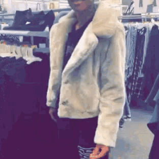a woman in a white fur coat is standing in a store
