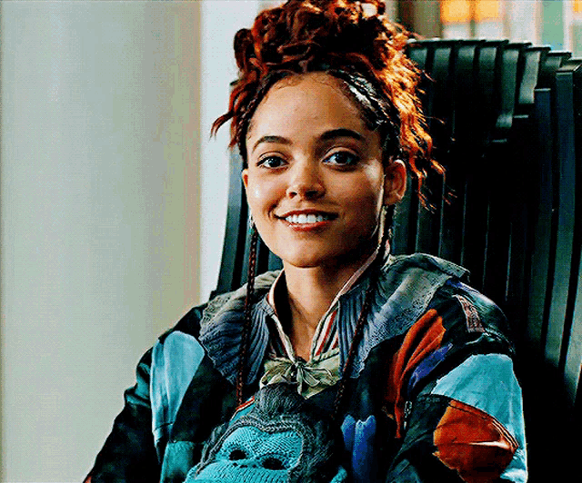 a woman with red hair is smiling and holding a stuffed animal