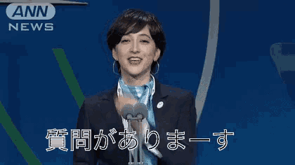 a woman in a suit and scarf is speaking into a microphone in front of a sign that says ann news