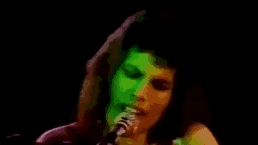 a close up of a person singing into a microphone with a green light behind them .