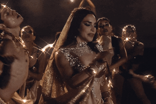 a woman wearing a necklace and a veil is dancing in a dark room