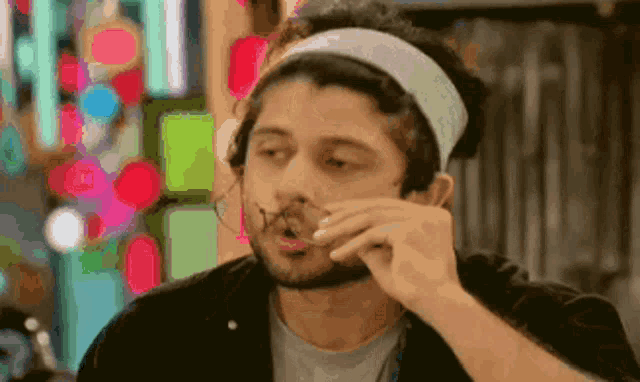 a man with a headband on his head is eating something from his hand .