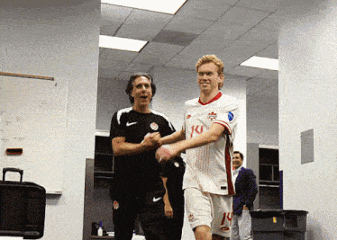 a soccer player with the number 14 on his shorts shakes hands with a coach