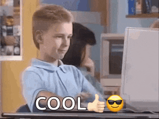 a young boy is giving a thumbs up while sitting at a desk in front of a computer .