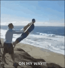 a man is holding a child up in the air on the beach .