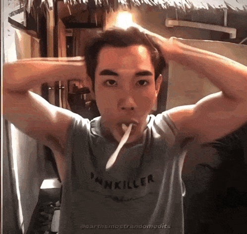 a man wearing a tank top that says pankiller is brushing his teeth with a toothbrush
