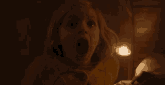 a little girl is screaming with her mouth wide open in a dark room .