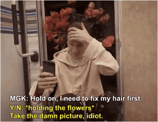 a man is holding his hand to his head while looking at his phone and holding flowers .