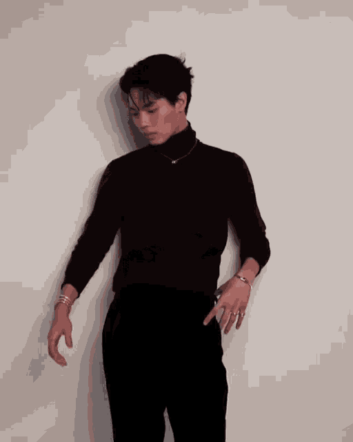 a man wearing a black turtleneck and a necklace with the letter r on it