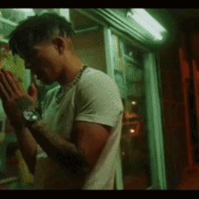 a man wearing a watch is praying in front of a window .