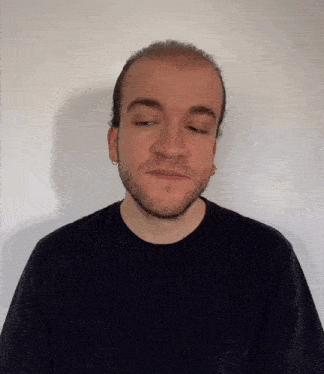 a man with a beard wearing a black shirt and earrings