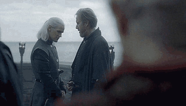 a man and a woman are standing next to each other holding hands .