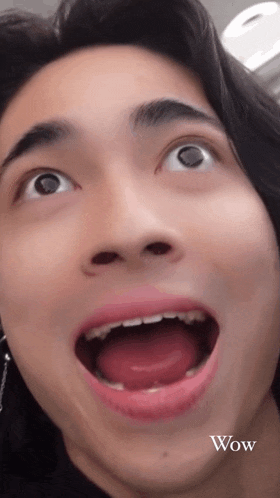 a close up of a man 's face with his mouth open and the word wow written below him