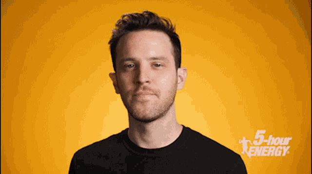 a man in a black shirt stands in front of a 5 hour energy ad