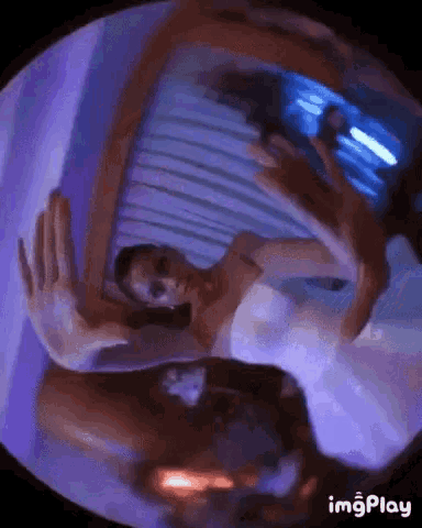 a woman in a white dress is dancing in front of a mirror with purple lights behind her .