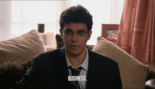a man in a suit and tie is sitting on a couch and saying business