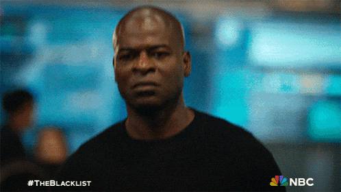 a man in a black shirt stands in front of a blue background with the nbc logo
