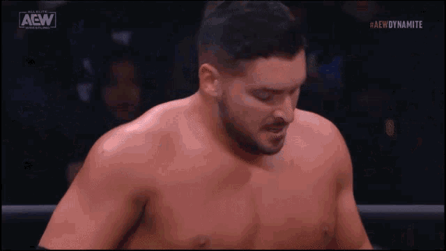 a shirtless wrestler in a ring with the aew logo on the bottom left