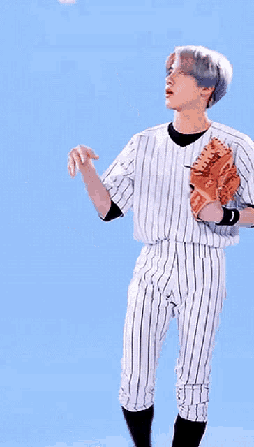 a man in a striped baseball uniform is holding a baseball glove and a ball .