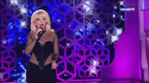 a woman singing into a microphone on a stage in front of a purple background that says pocchr