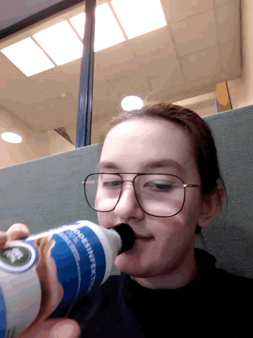a girl with glasses is drinking from a bottle that says " does n't expire "