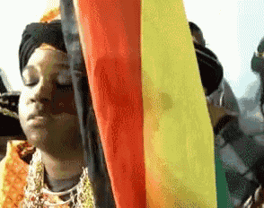 a woman with her eyes closed holds a rainbow flag